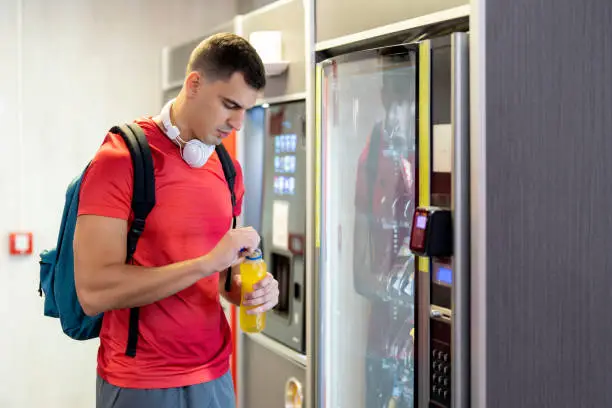 Atleta in palestra che consuma una bevanda dal distributore automatico di snack e bevande