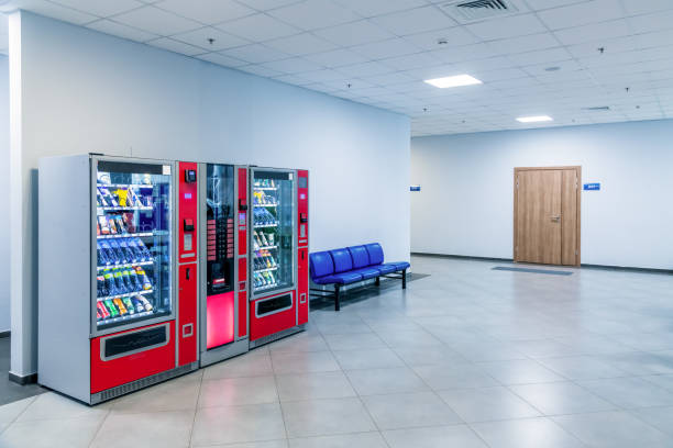 Group of red vending machines stands by the wall inside public building.