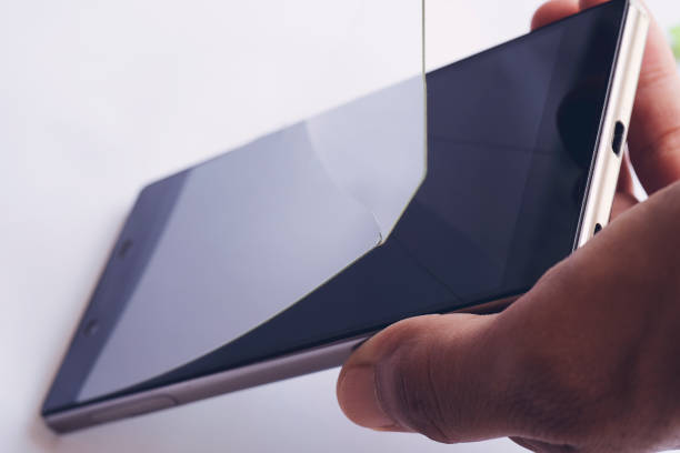 Mão removendo filme protetor de tela danificado e manchado do smartphone