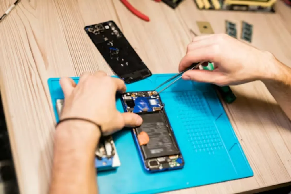 Manos de un técnico reparando un dispositivo con pinzas